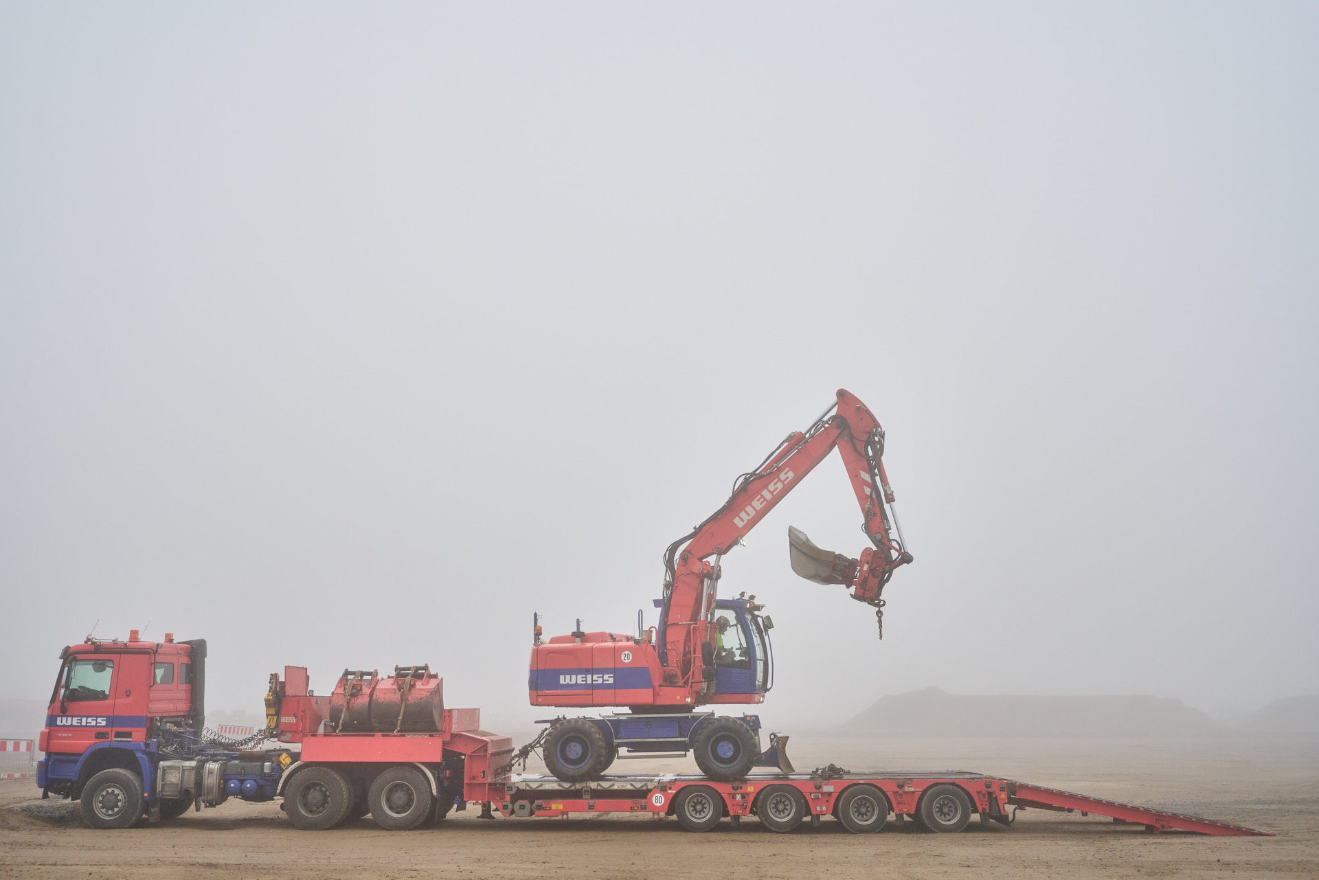 Baustellenfotografie Verladen Eines Baggers auf Tieflader im Nebel